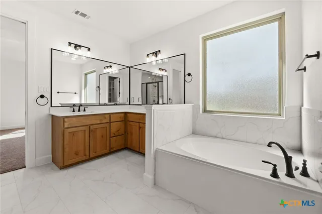 a bathroom with a tub sink and mirror
