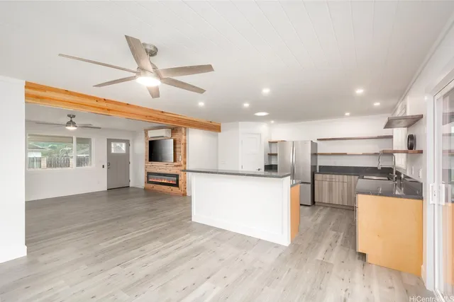 a view of a kitchen with kitchen island a counter top space wooden floor stainless steel appliances and cabinets