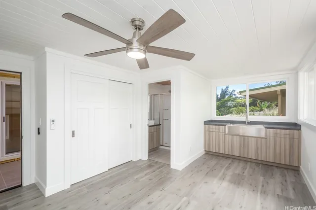 an empty room with wooden floor cabinet and a ceiling fan