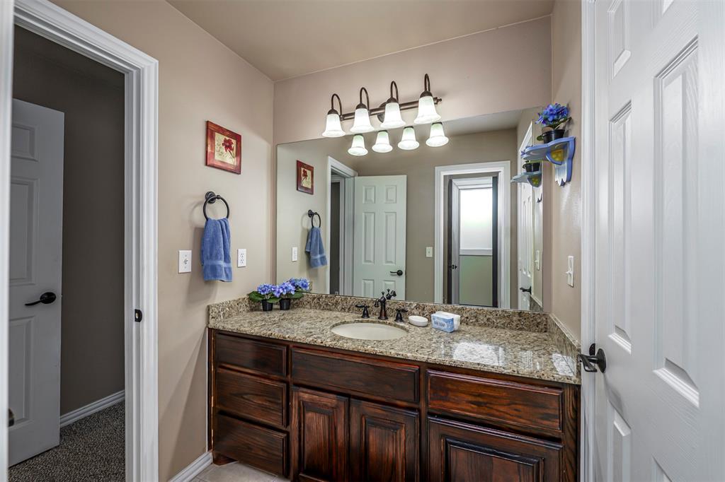 100 Manders Court Runaway Bay, TX 76426 - Photo 23 of 33 a bathroom with a granite countertop sink a large mirror and a wooden cabinets