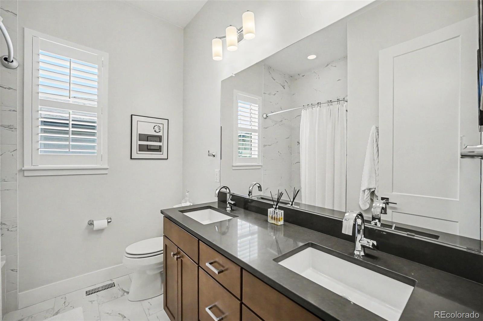 2101 Rim Ridge Drive Castle Pines, CO 80108 - Photo 26 of 50 a bathroom with a double vanity sink a toilet and a mirror
