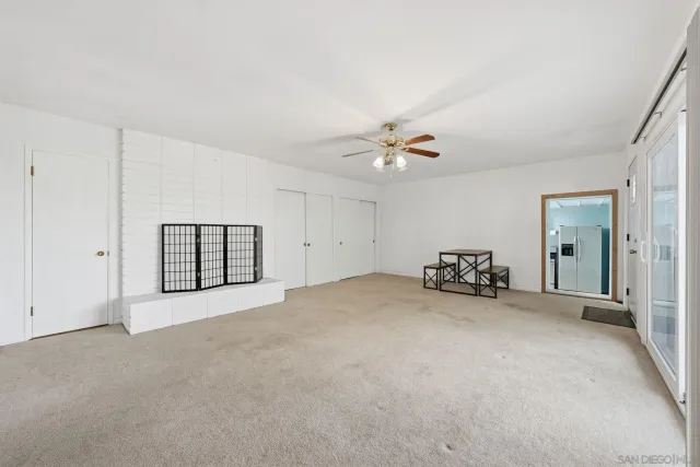 an empty room with windows and a ceiling fan