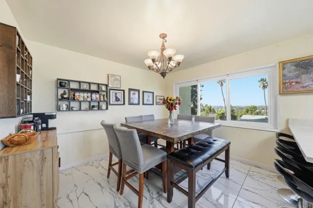 a view of a dining room with furniture a chandelier and large windows