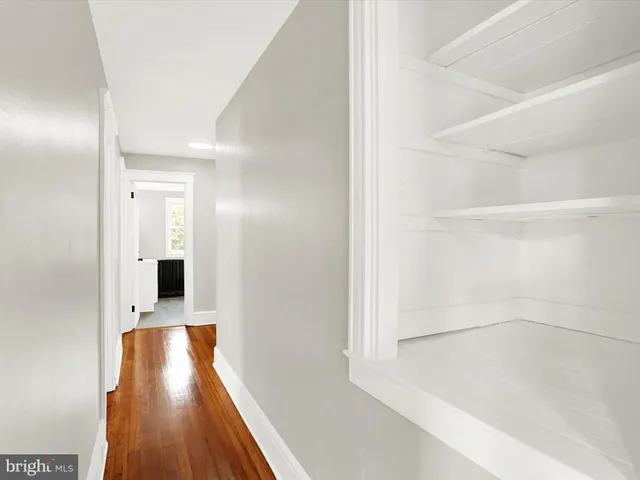 a view of a hallway with wooden floor and a bathroom