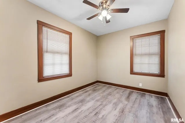an empty room with wooden floor chandelier and windows