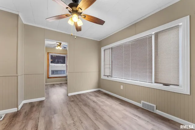a view of an empty room with a window and wooden floor