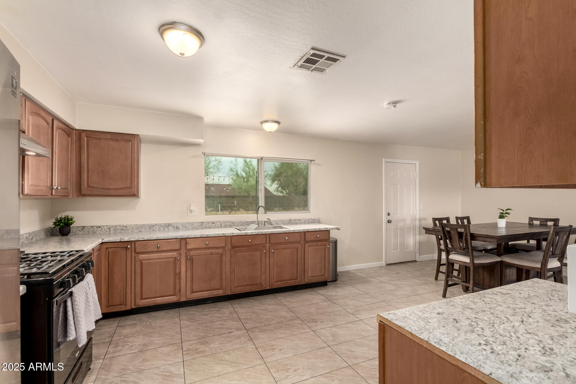2024 West Roeser Road Phoenix, AZ 85041 - Photo 17 of 36 a kitchen with granite countertop sink a stove a dining table and chairs