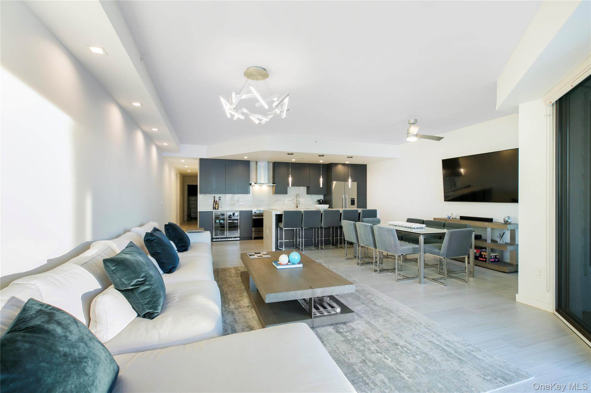 260 Dune Road, Unit 101G Westhampton Beach, NY 11978 - Photo 5 of 16 a living room with furniture kitchen view and a flat screen tv