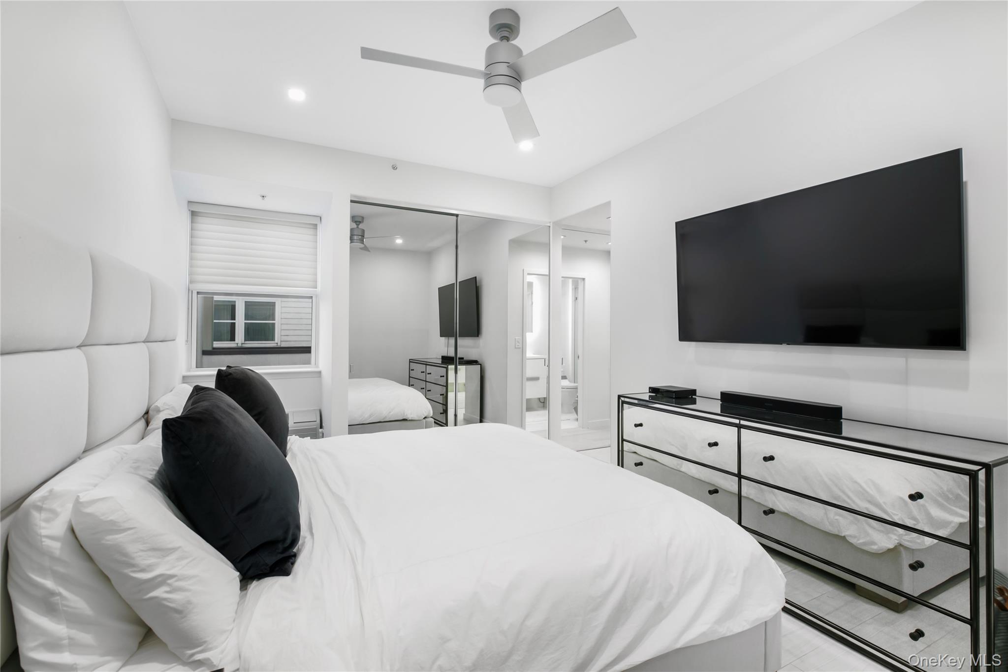 260 Dune Road, Unit 101G Westhampton Beach, NY 11978 - Photo 9 of 16 a bedroom with a bed a tv and wooden floor