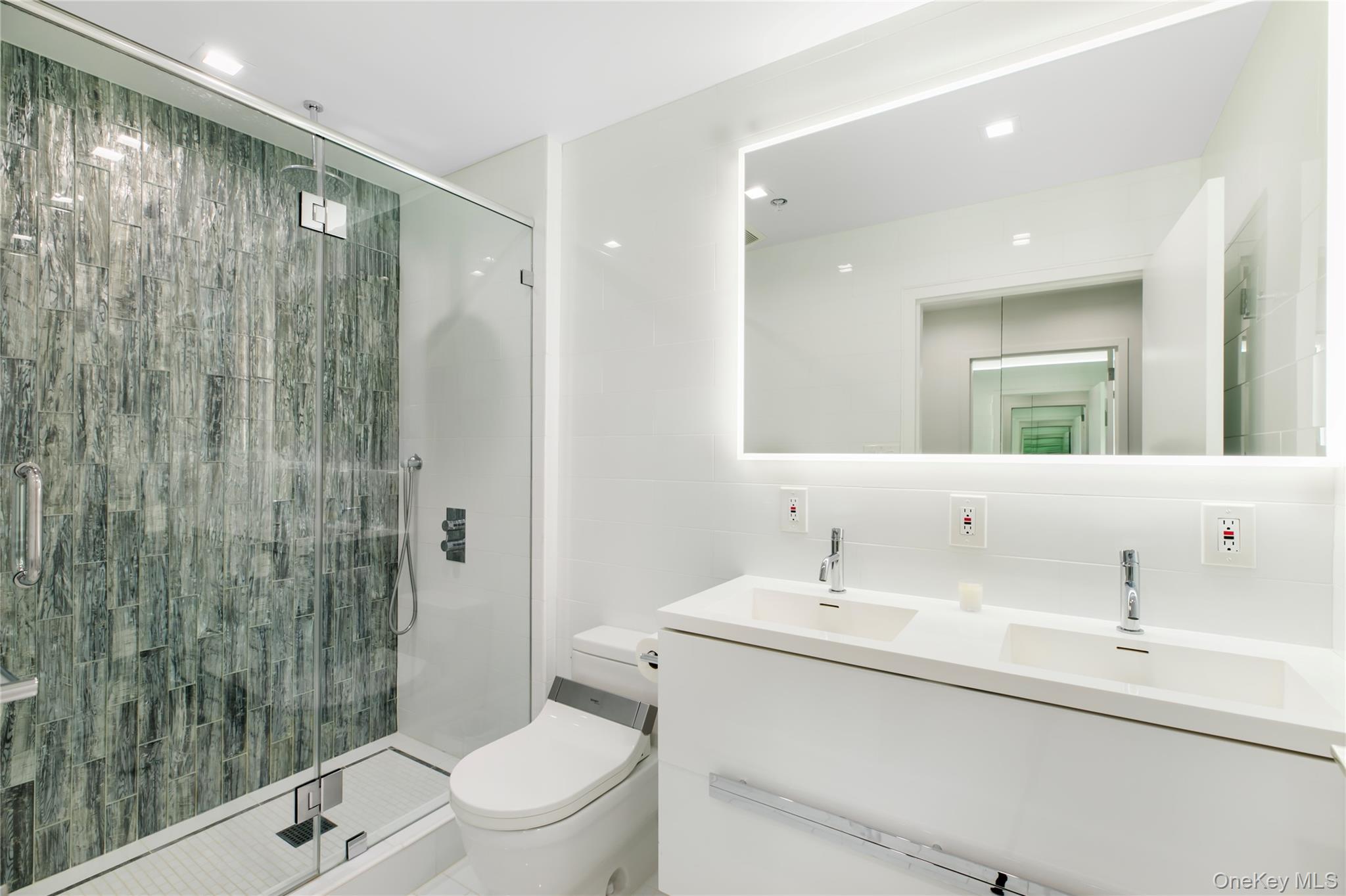 260 Dune Road, Unit 101G Westhampton Beach, NY 11978 - Photo 10 of 16 a bathroom with a toilet a sink a mirror a shower and vanity