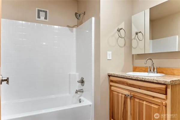 a bathroom with a granite countertop sink a mirror and a bathtub