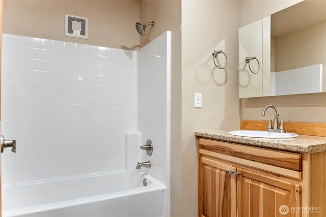 a bathroom with a granite countertop sink a mirror and a bathtub