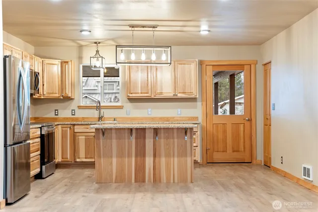 a kitchen with stainless steel appliances granite countertop a stove a sink and a refrigerator