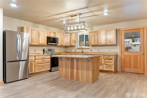 a kitchen with stainless steel appliances granite countertop a refrigerator a stove top oven a sink and dishwasher with wooden floor