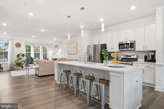 a kitchen with kitchen island granite countertop lots of white cabinets appliances and furniture