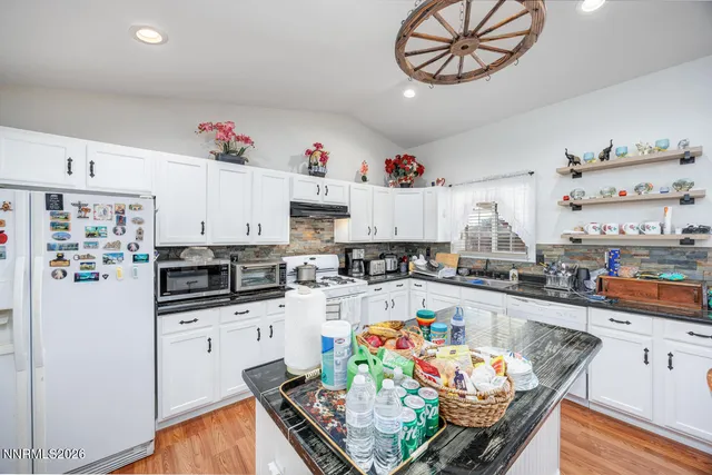 a kitchen with granite countertop a white stove top oven cabinets and living room view