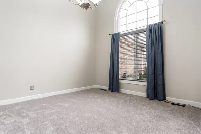 an empty room with fireplace fan and windows