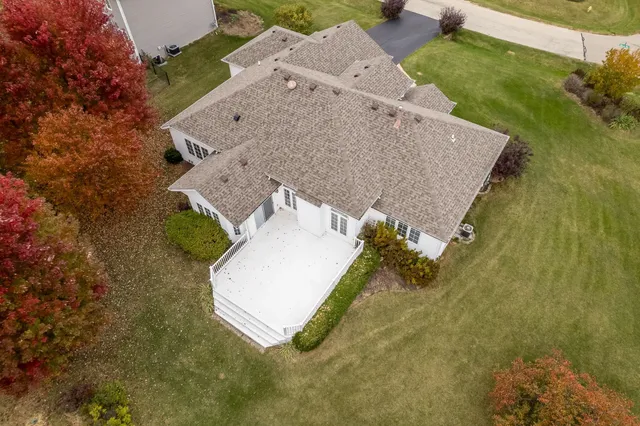 an aerial view of a house with a yard and trees all around