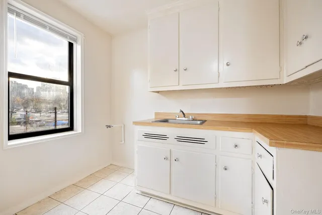 a view of cabinets a sink and a stove in a white room