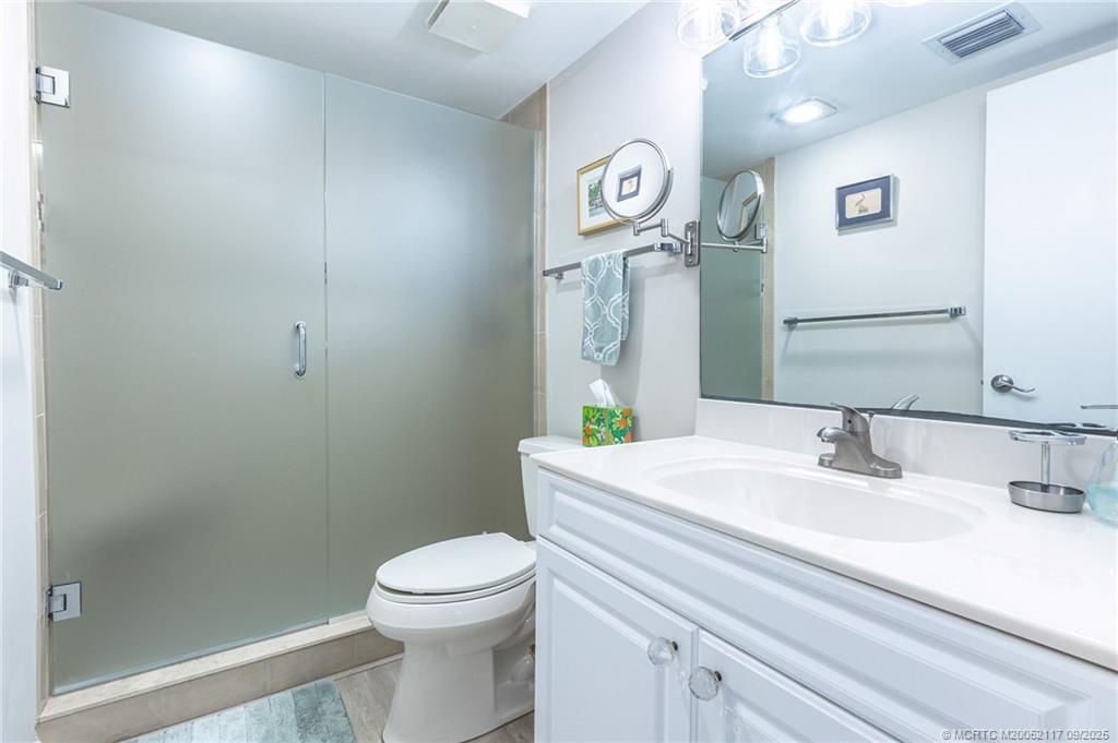 5596 Northeast Gulfstream Way Stuart, FL 34996 - Photo 17 of 21 a bathroom with a sink a toilet and a mirror