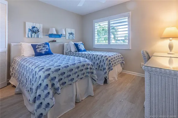a bedroom with a bed and a lamp on table with wooden floor
