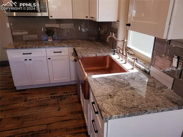 a large kitchen with a sink a refrigerator and wooden floor