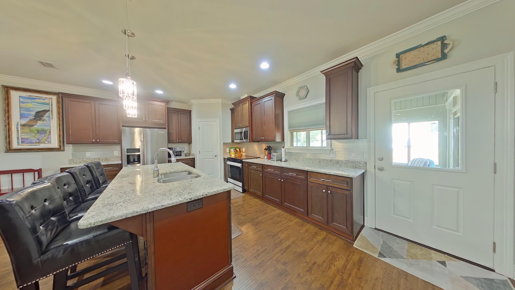 8686 El Paseo Street Navarre, FL 32566 - Photo 8 of 39 a large kitchen with kitchen island a sink a stove a dining table and chairs