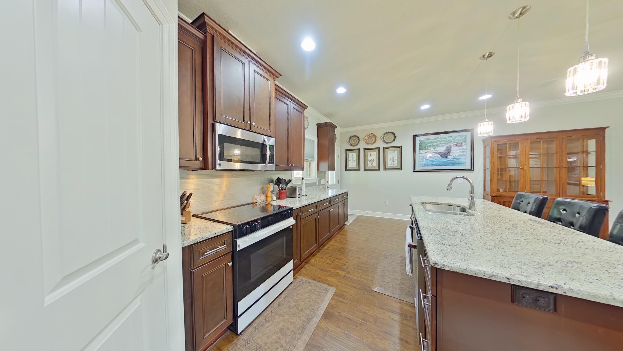 8686 El Paseo Street Navarre, FL 32566 - Photo 9 of 39 a kitchen with stainless steel appliances granite countertop a stove top oven a sink dishwasher a dining table and chairs with wooden floor