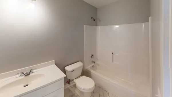 a white toilet sitting next to a bathroom sink and a shower