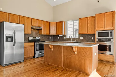 a kitchen with granite countertop a refrigerator stove top oven and sink