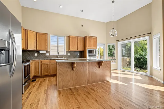 a kitchen with stainless steel appliances granite countertop a refrigerator a sink dishwasher a stove and white countertops with wooden floor
