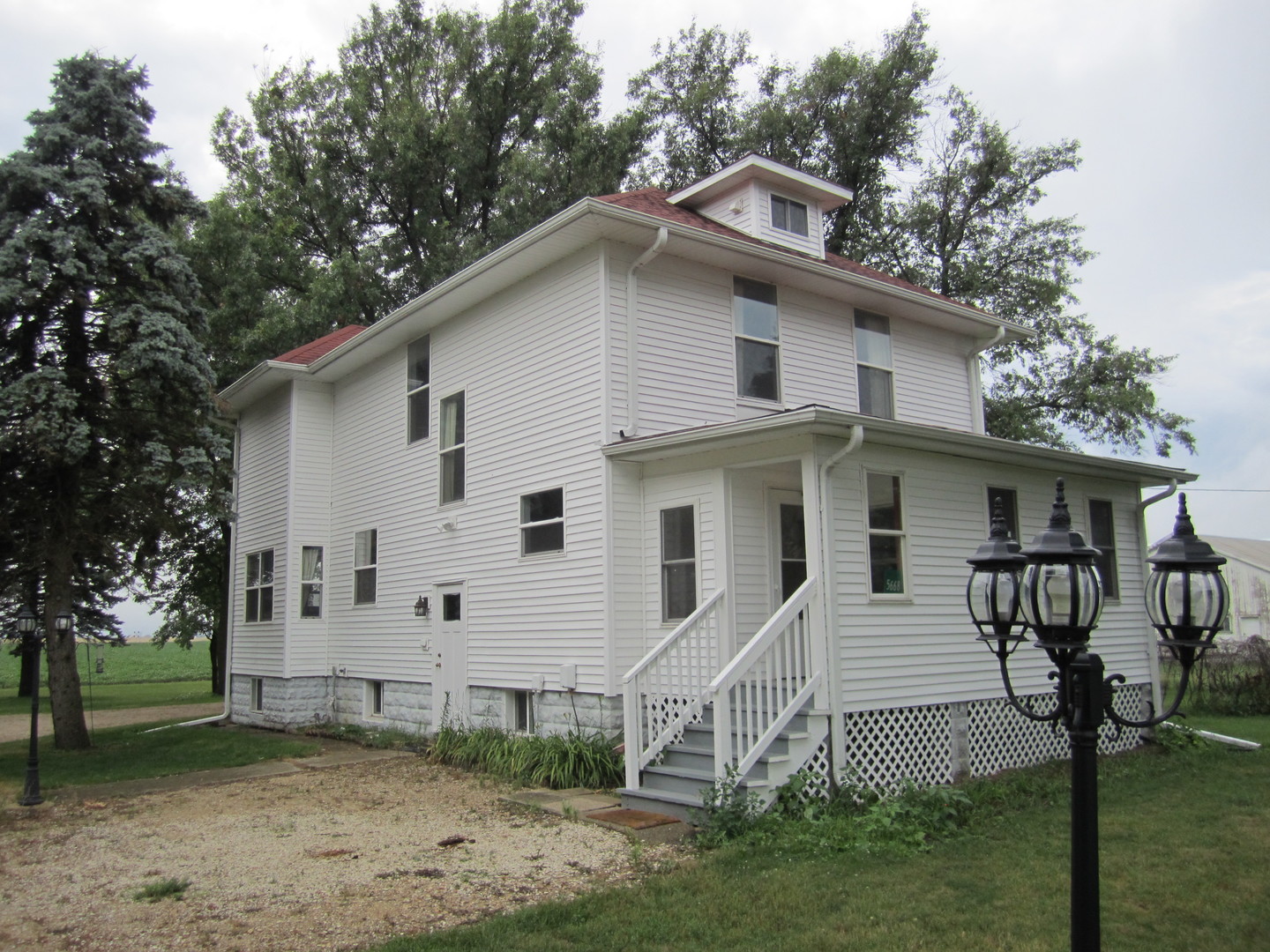 a view of a white house next to a yard with large trees