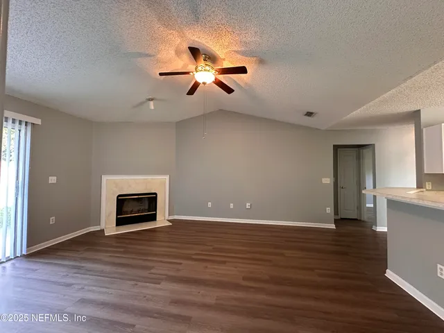 an empty room with wooden floor fireplace and windows