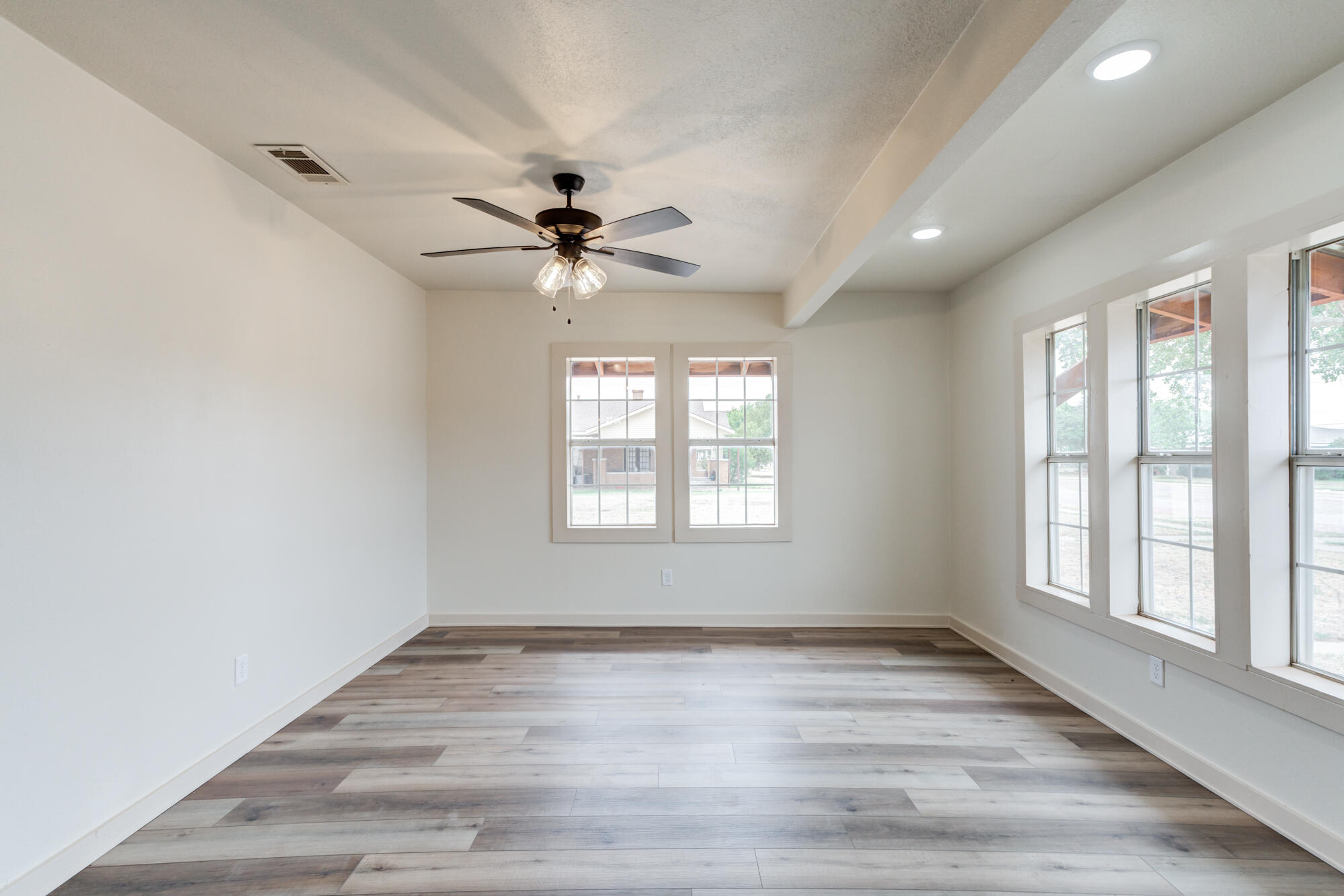 315 West Garza Street Slaton, TX 79364 - Photo 11 of 35 an empty room with wooden floor and windows
