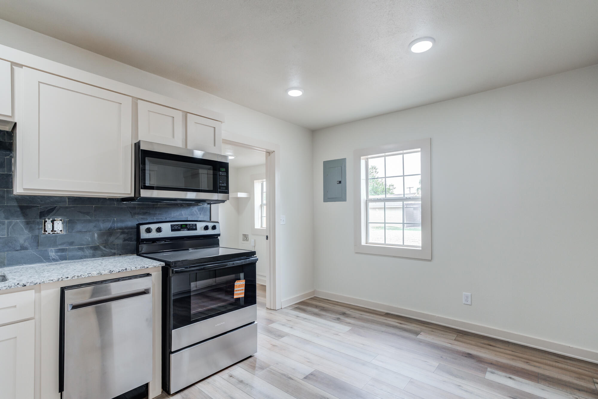 315 West Garza Street Slaton, TX 79364 - Photo 14 of 35 a kitchen with granite countertop white cabinets stainless steel appliances and window