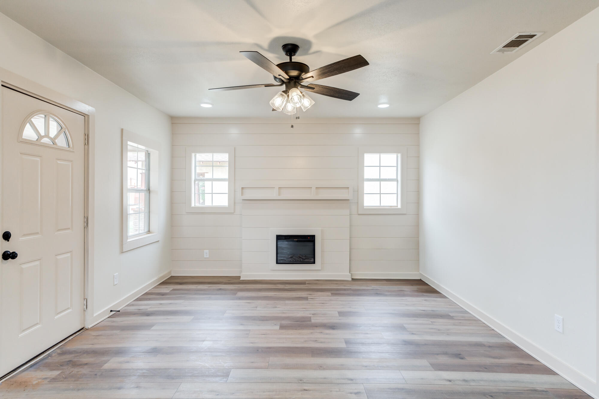315 West Garza Street Slaton, TX 79364 - Photo 5 of 35 an empty room with wooden floor ceiling fan and windows