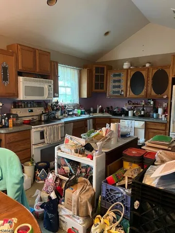 a utility room with stainless steel appliances lots of clutter and cabinets