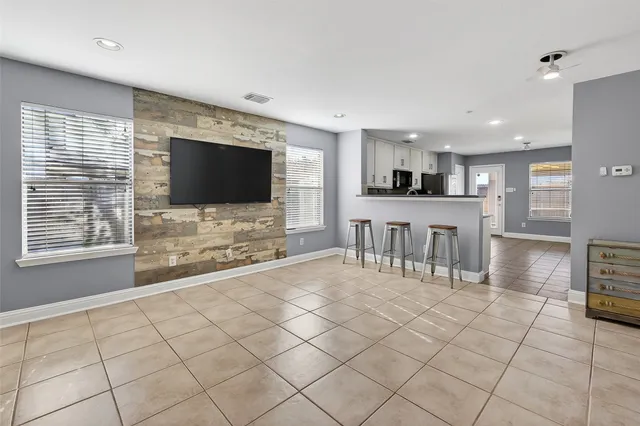 a view of an empty room with kitchen and window