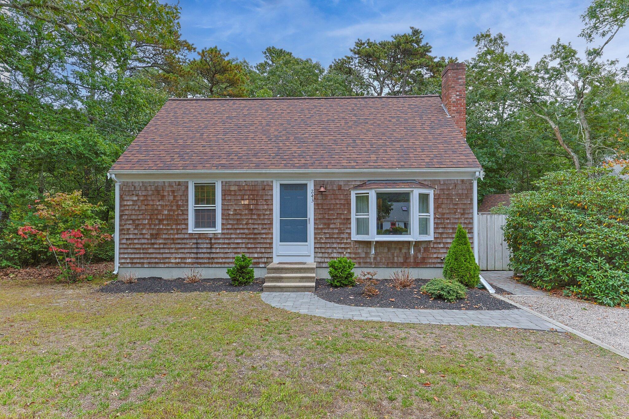 243 Commons Way Brewster, MA 02631 - Photo 2 of 32 a front view of a house with garden