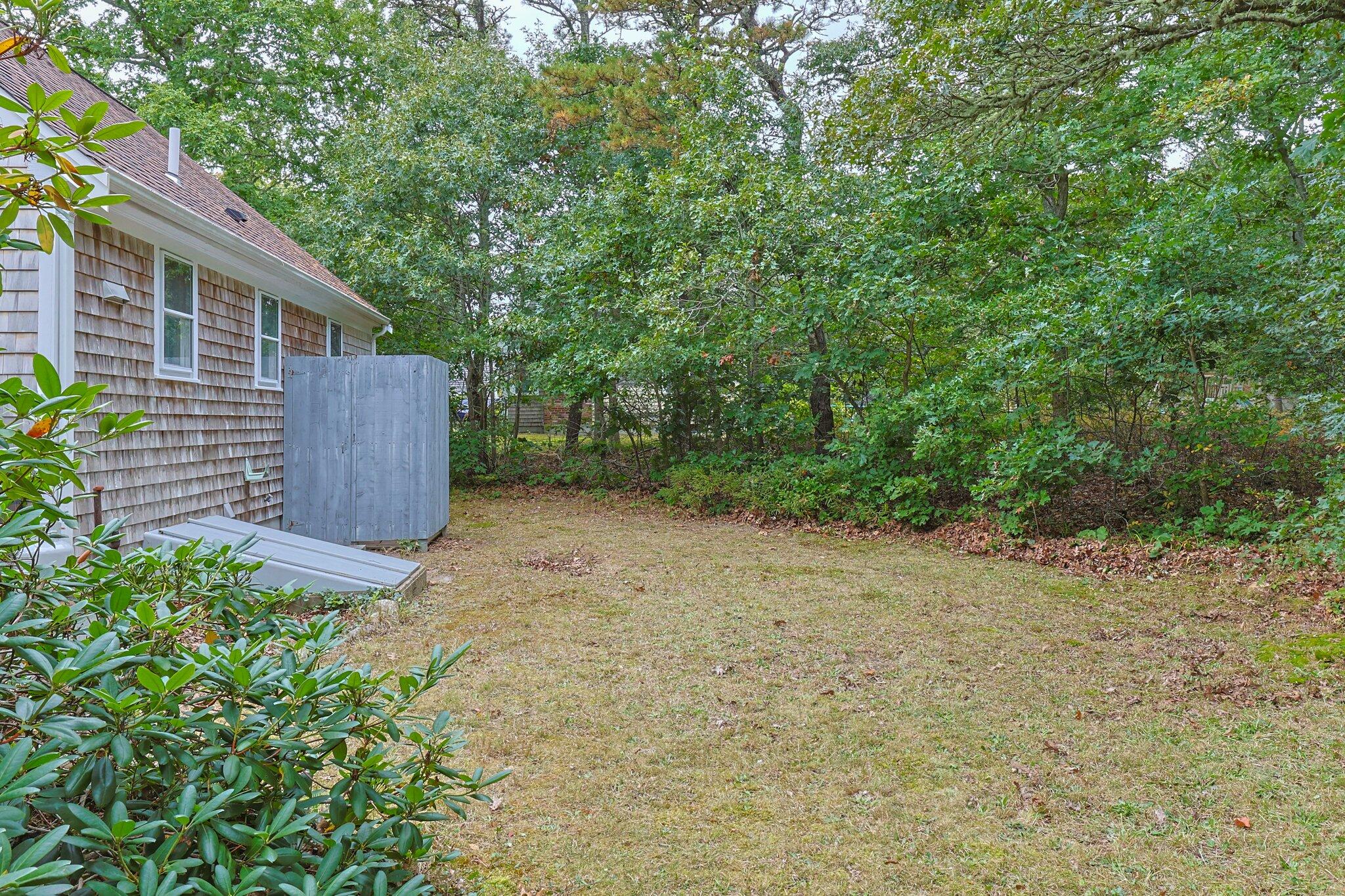 243 Commons Way Brewster, MA 02631 - Photo 28 of 32 a backyard of a house with lots of green space