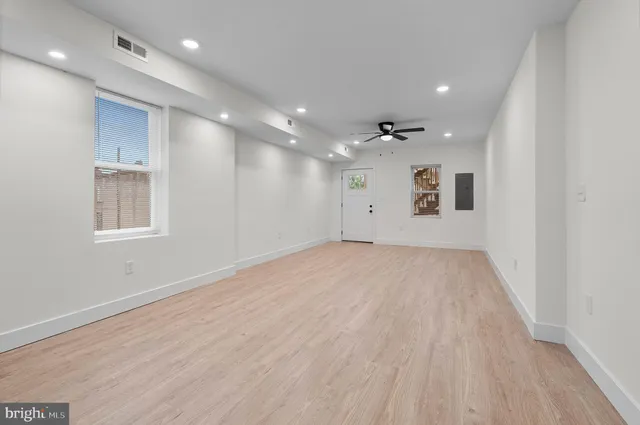an empty room with wooden floor and windows