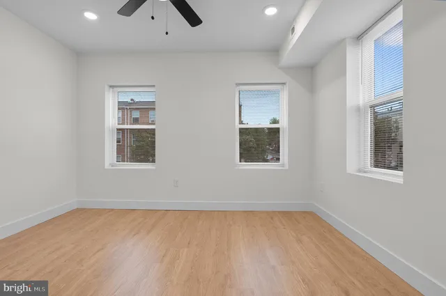 a view of empty room with wooden floor and fan