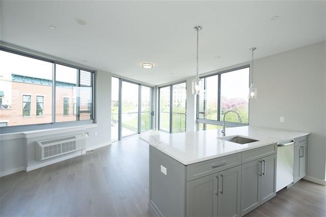 a hall with kitchen island a sink wooden floor and a large window