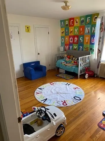 a view of an empty room with wooden floor and closet