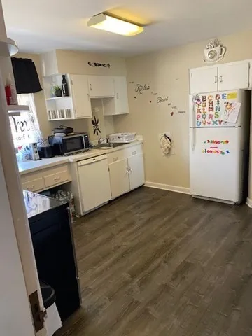 a kitchen with granite countertop a refrigerator a stove a sink and dishwasher with wooden floor