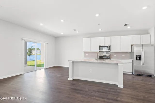 a kitchen with stainless steel appliances granite countertop a stove top oven a sink and a refrigerator