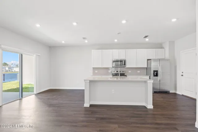a view of kitchen with stainless steel appliances granite countertop a stove top oven a sink and a refrigerator