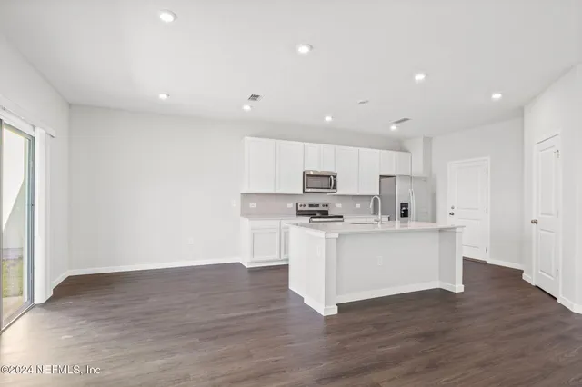 a kitchen with stainless steel appliances white cabinets and wooden floor