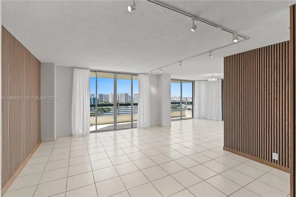 a view of an empty room with kitchen and window