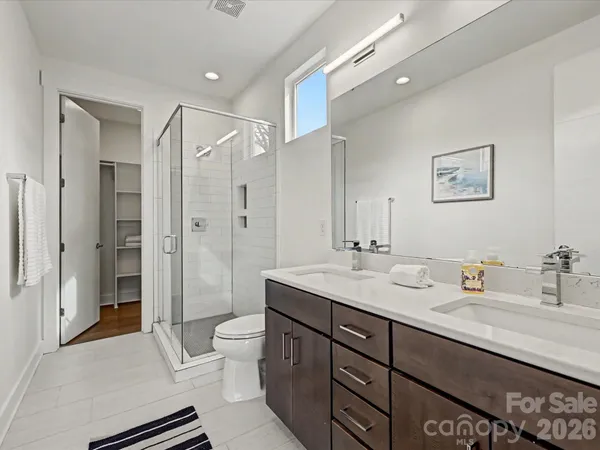 a spacious bathroom with a double vanity sink toilet mirror and shower